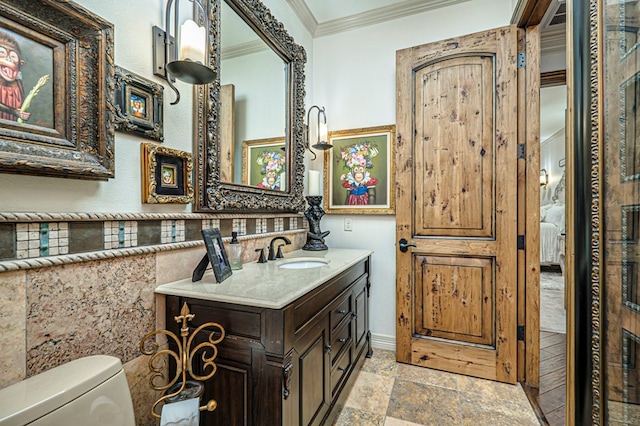 bathroom with toilet, vanity, and ornamental molding