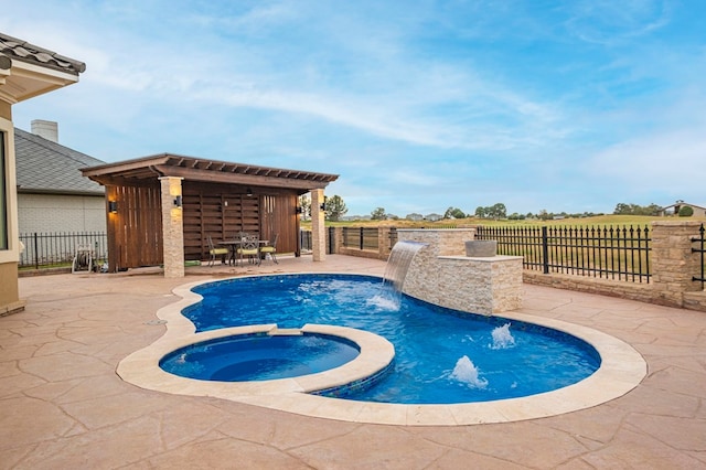 view of pool featuring an in ground hot tub, pool water feature, and a patio