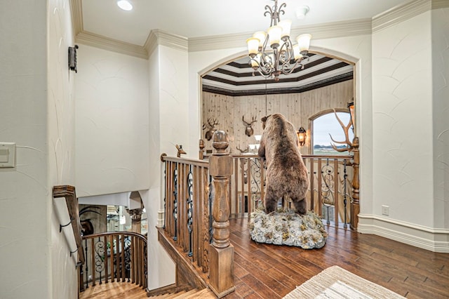 staircase featuring hardwood / wood-style floors, ornamental molding, and an inviting chandelier