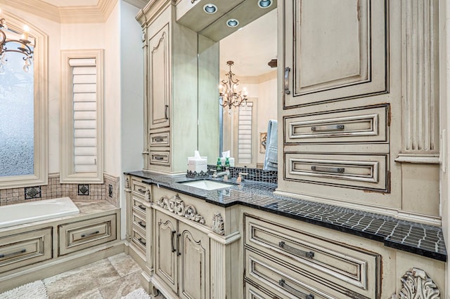 bathroom featuring a bathing tub, vanity, a notable chandelier, and ornamental molding