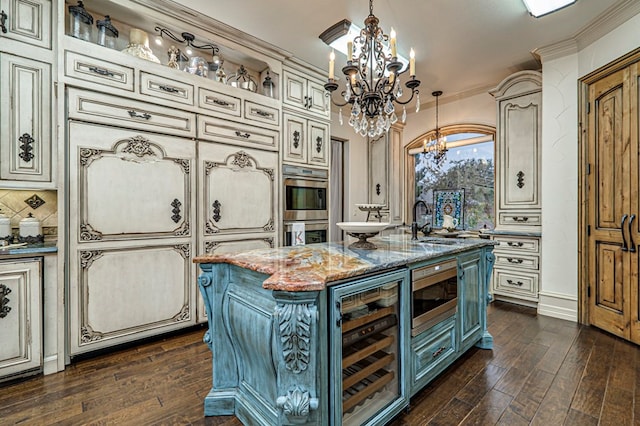 kitchen with beverage cooler, cream cabinets, decorative light fixtures, dark stone countertops, and an island with sink