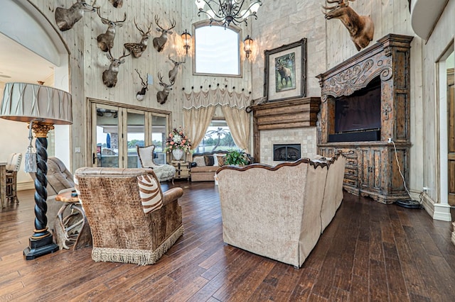 living room with dark hardwood / wood-style floors, a towering ceiling, and a tile fireplace