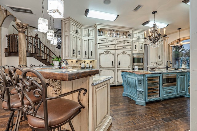 kitchen with cream cabinetry, decorative light fixtures, and kitchen peninsula