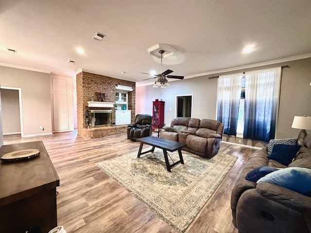 living room with a fireplace, crown molding, light hardwood / wood-style flooring, and ceiling fan