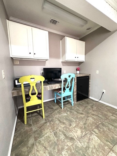 kitchen with ornamental molding, built in desk, and white cabinets