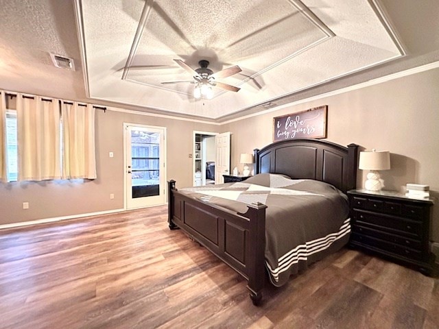 bedroom featuring ceiling fan, wood-type flooring, ornamental molding, a textured ceiling, and a raised ceiling