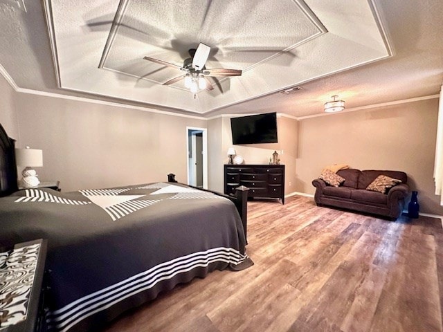 bedroom with crown molding, a textured ceiling, ceiling fan, and a tray ceiling