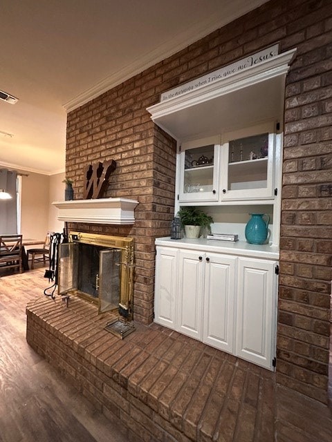 bar featuring ornamental molding, a fireplace, dark hardwood / wood-style flooring, and white cabinets