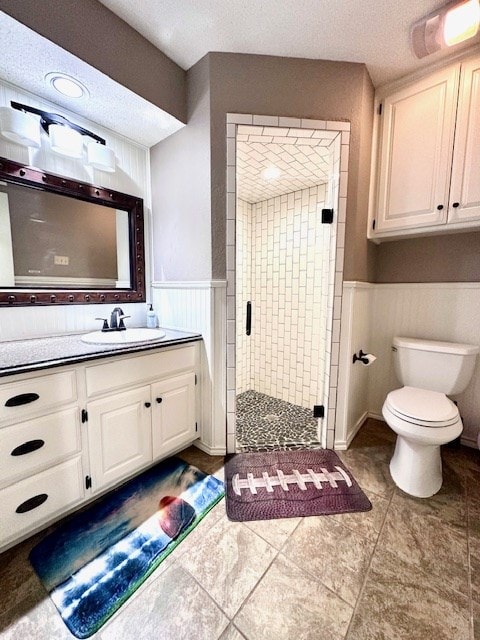 bathroom featuring vanity, a shower with door, toilet, and a textured ceiling