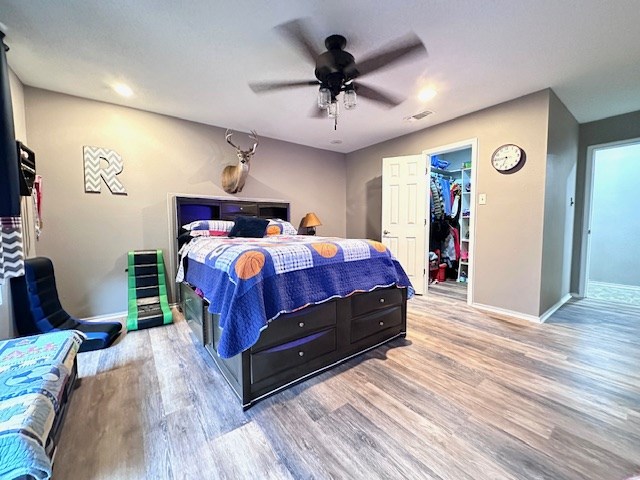 bedroom featuring a closet, a spacious closet, ceiling fan, and light hardwood / wood-style floors