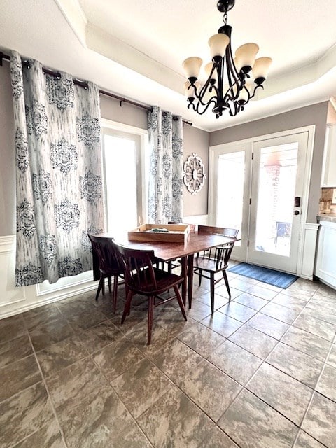 dining area with a raised ceiling and a notable chandelier