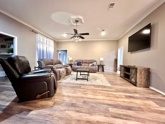 living room with ceiling fan, ornamental molding, and light wood-type flooring