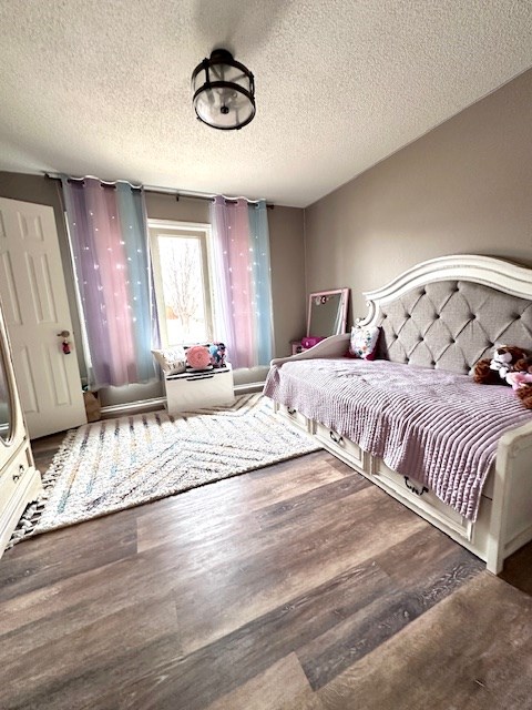 bedroom with dark wood-type flooring and a textured ceiling