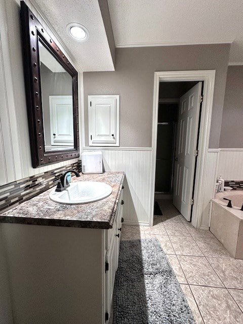 bathroom featuring tile patterned flooring, vanity, a textured ceiling, and a bathtub