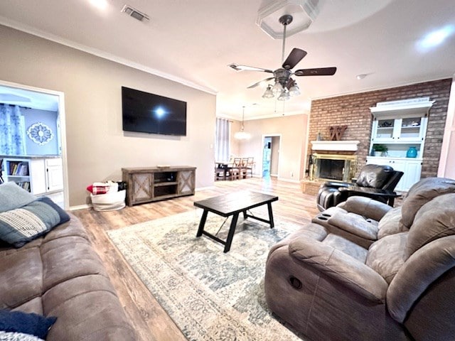 living room featuring a brick fireplace, crown molding, and light hardwood / wood-style flooring