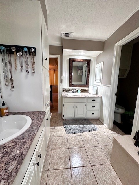 bathroom with tile patterned floors, toilet, a textured ceiling, and vanity