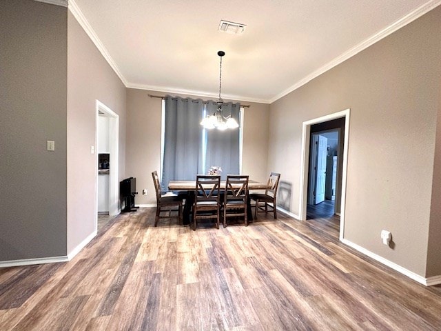 dining room featuring crown molding, wood-type flooring, and an inviting chandelier