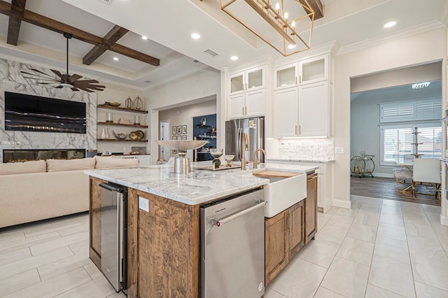 kitchen featuring a center island with sink, appliances with stainless steel finishes, glass insert cabinets, open floor plan, and white cabinets