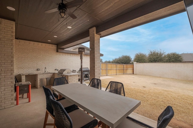 view of patio / terrace featuring ceiling fan, a fenced backyard, a grill, exterior kitchen, and outdoor dining space