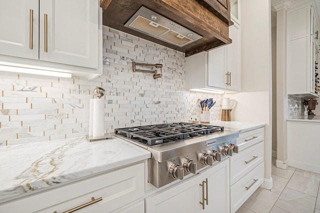 kitchen with light stone countertops, white cabinetry, stainless steel gas stovetop, and custom exhaust hood