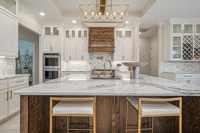 kitchen featuring glass insert cabinets, stainless steel double oven, and a tray ceiling