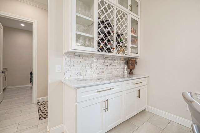 bar featuring baseboards, a bar, light tile patterned floors, and tasteful backsplash