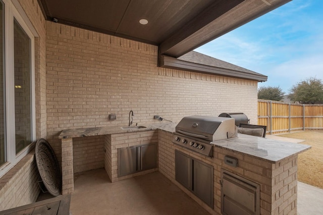 view of patio featuring exterior kitchen, a sink, area for grilling, and fence