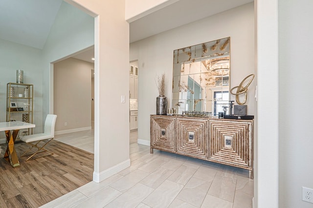 interior space with baseboards, wood finished floors, vaulted ceiling, vanity, and a notable chandelier