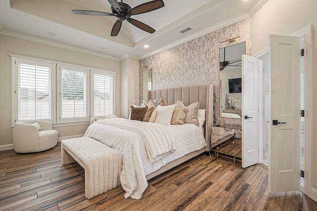 bedroom with ornamental molding, wood finished floors, a raised ceiling, and visible vents