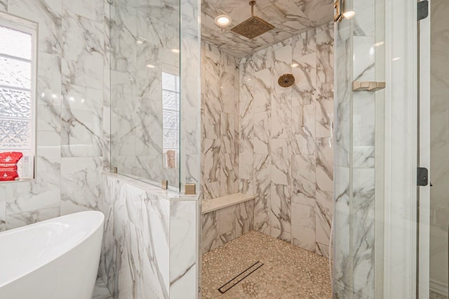 full bathroom with a freestanding tub, a marble finish shower, and tile walls