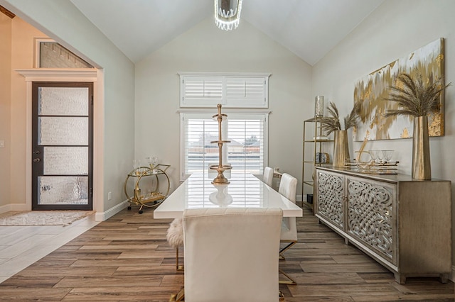 dining room featuring dark wood-style floors, high vaulted ceiling, and baseboards