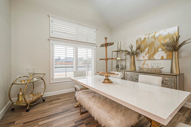 dining room with lofted ceiling, light wood finished floors, and baseboards