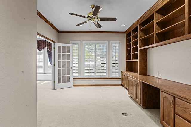 unfurnished office featuring ceiling fan, light carpet, baseboards, and ornamental molding