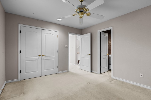 unfurnished bedroom with ensuite bath, light colored carpet, baseboards, and a closet