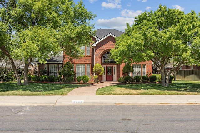 view of front of property with brick siding, a front lawn, and fence