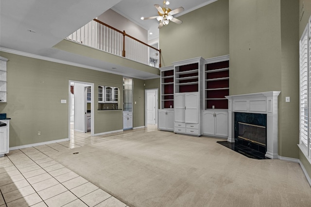 unfurnished living room featuring ornamental molding, a high ceiling, and a ceiling fan