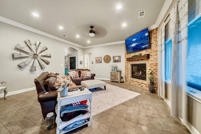 living room with hardwood / wood-style floors, a brick fireplace, ceiling fan, and crown molding