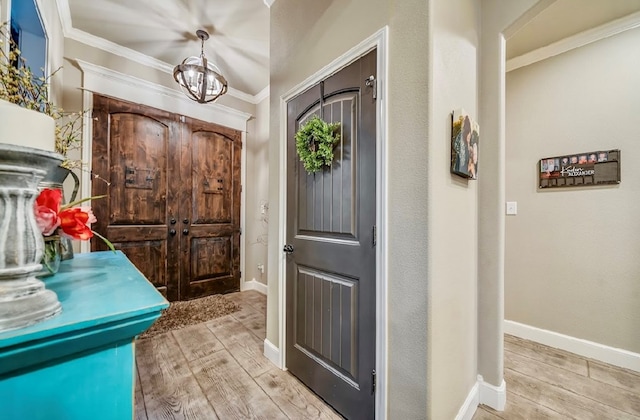 foyer featuring a notable chandelier, light wood-type flooring, and crown molding