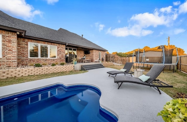 view of swimming pool with a patio area and a trampoline