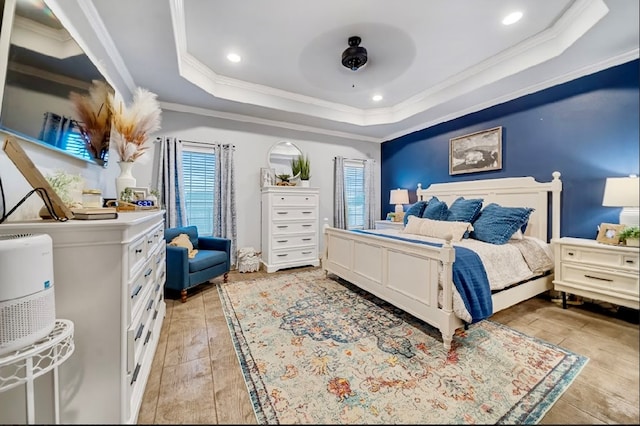 bedroom with light hardwood / wood-style floors, a raised ceiling, and crown molding