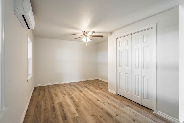 unfurnished bedroom featuring a wall mounted AC, ceiling fan, a closet, and light wood-type flooring