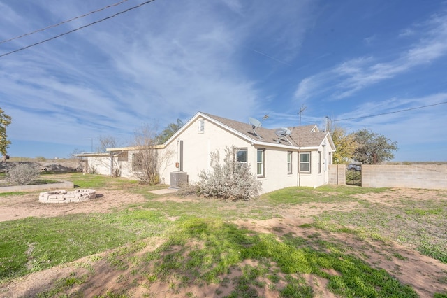 view of property exterior with cooling unit and a lawn