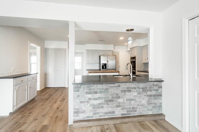 kitchen with kitchen peninsula, appliances with stainless steel finishes, light hardwood / wood-style floors, and sink