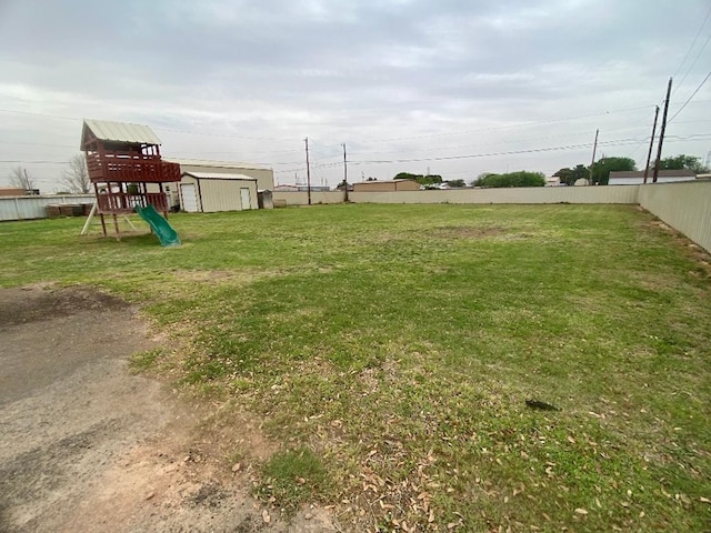 view of yard with an outdoor structure, a playground, a shed, and fence