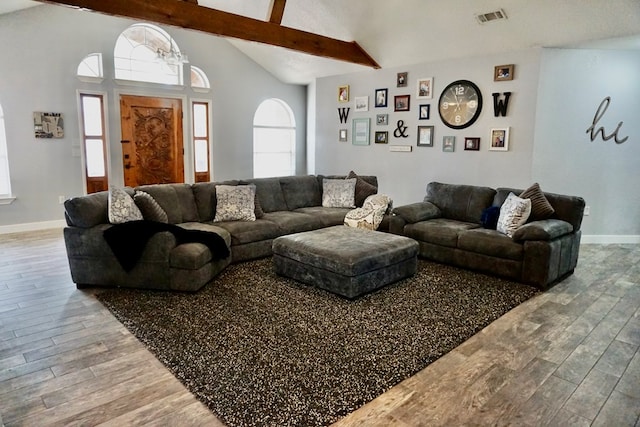 living room featuring baseboards, lofted ceiling with beams, wood finished floors, and visible vents