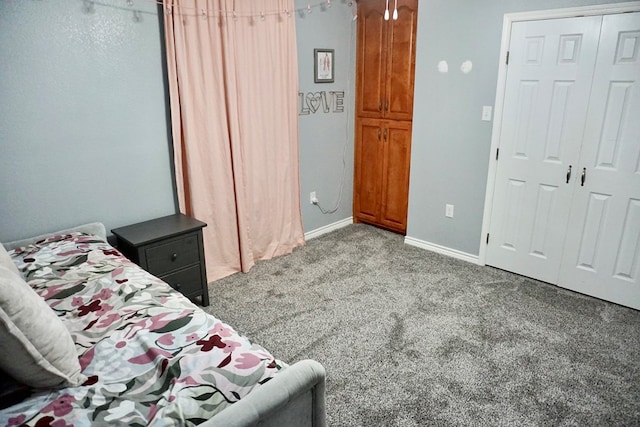 carpeted bedroom featuring baseboards and a closet