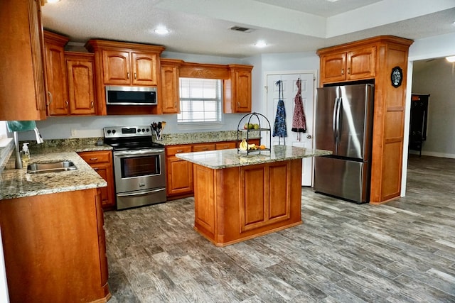 kitchen with a sink, light stone countertops, stainless steel appliances, and visible vents