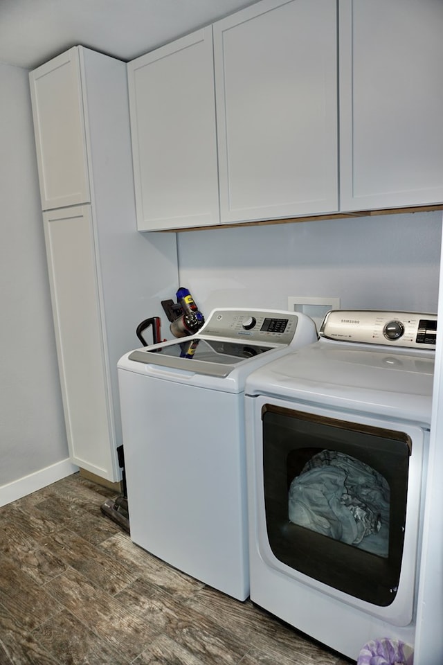 laundry room featuring cabinet space, separate washer and dryer, baseboards, and wood finished floors