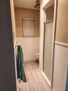 bathroom featuring hardwood / wood-style floors, an enclosed shower, and toilet