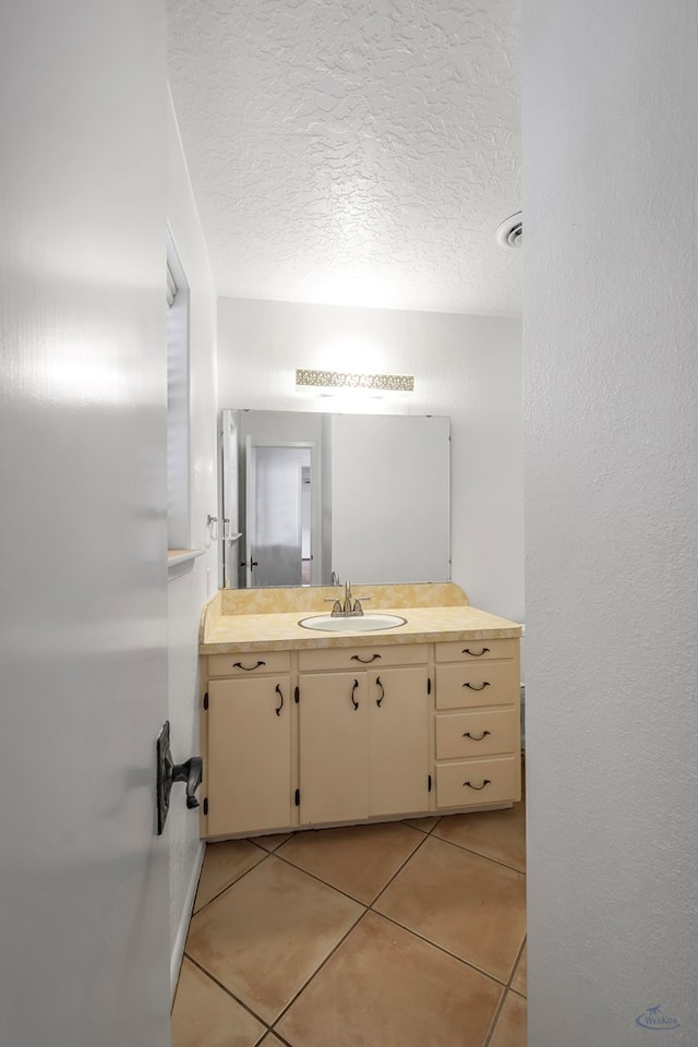 bathroom with tile patterned flooring, vanity, and a textured ceiling